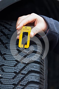 Woman measures tire tread of a car tire