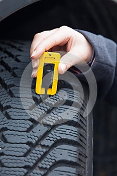 Woman measures tire tread of a car tire