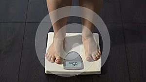 Woman measuring body weight on scales, healthy dieting, balanced nutrition