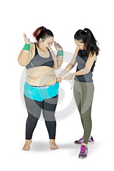 Woman measuring the fat belly of another woman