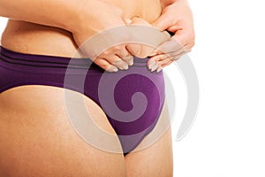 Woman measuring fat belly in underwear