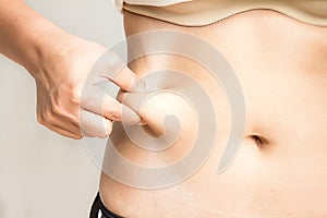 Woman measuring her belly fat