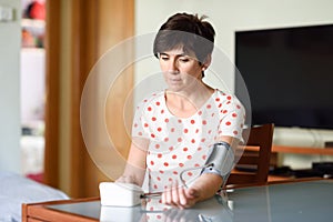 Woman measuring her own blood pressure at home.