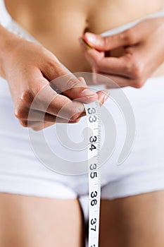 Woman measuring her slim body. Isolated on white background.