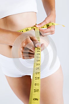 Woman measuring her slim body. Isolated on white background.