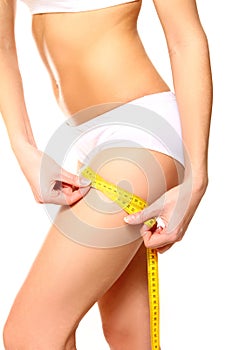 Woman measuring her thigh with a yellow metric tape measure