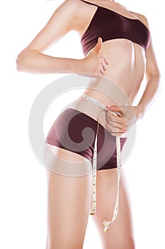 Woman measuring her waist by metric tape isolated