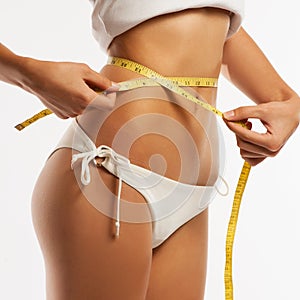 Woman measuring her waistline .