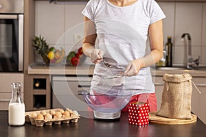 Woman measuring and sieving flour