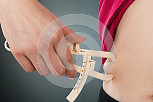 Woman Measuring Stomach Fat With Caliper