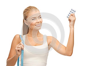 Woman with measuring tape and diet pills