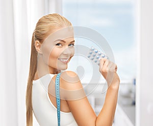 Woman with measuring tape and diet pills