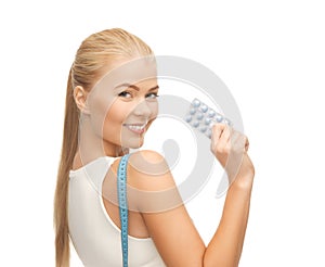 Woman with measuring tape and diet pills