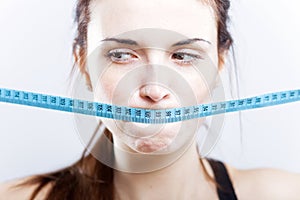 Woman with measuring tape on mouth