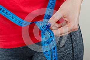 Woman measuring waist circumference with tape