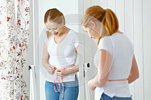Woman measuring waist in front of mirror