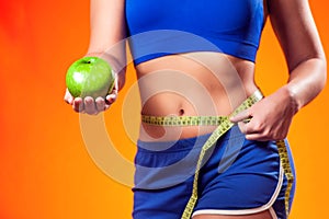 Woman measuring waist and holding apple. People, fitness and healthcare concept