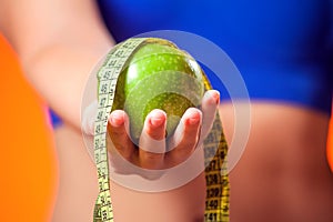 Woman measuring waist and holding apple. People, fitness and healthcare concept