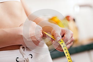 Woman measuring waist with tape