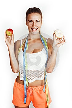 woman measuring waist with tape having choise between apple and donut isolated on white background