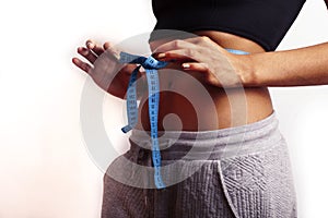 woman measuring waist with tape on knot, african tan isolated