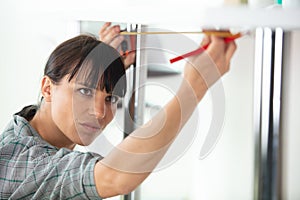 woman measuring wall in kitchen