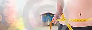 Woman measuring weight with measuring tape on waist near summer beach huts with transition