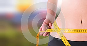 Woman measuring weight with measuring tape on waist in Summer