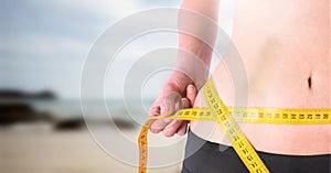 Woman measuring weight with measuring tape on waist on Summer beach