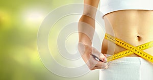 Woman measuring weight with measuring tape on waist on Summer beach