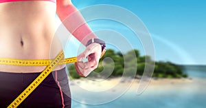 Woman measuring weight with measuring tape on waist on tropical paradise Summer beach