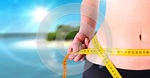 Woman measuring weight with measuring tape on waist on tropical paradise Summer beach