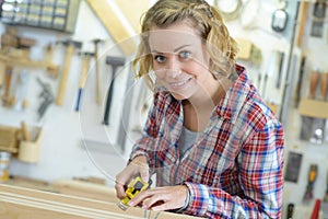 Woman measuring wooden board with tape measure