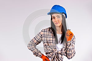 Woman mechanic in blue hard hat and gloves posing with a wrench on a white background and side space.
