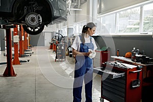 Woman mechanic choosing correct tool for car repair