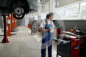 Woman mechanic choosing correct tool for car repair photo