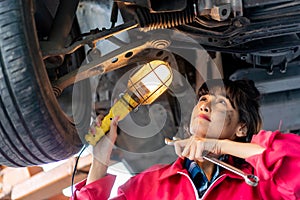 Woman Mechanic Examining Under the Car at the Repair Garage