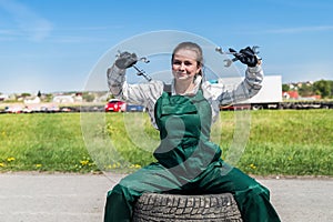 Woman mechanic posing with spanners and tyres