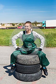 Woman mechanic posing with spanners and tyres