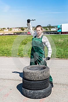 Woman mechanic posing with spanners and tyres