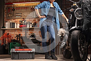 Woman mechanic standing beside a vintage motorbike