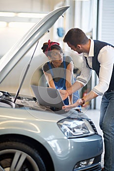 Woman mechanics check the diagnostics on laptop at car