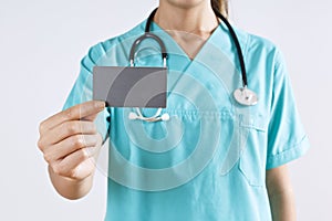 Woman medical doctor hand holding a blank card on gray background.