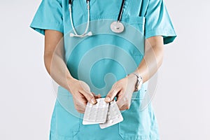 Woman medical doctor hands holding the pills on gray background.