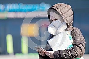 Woman with medical face mask near supermarket store reading internet news