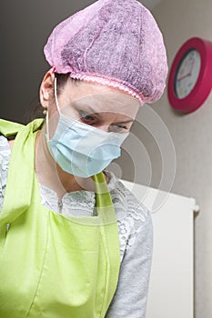 Woman in medical mask and cap. Cooking at home in isolation during an epidemic. Close-up shot