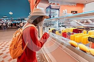 Woman in a medical mask during the covid-19 outbreak walks in the park and chooses a delicious ice cream in the refrigerator in