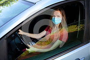 Woman in medical mask is driving the car. Coronavirus time. Dangerous situation