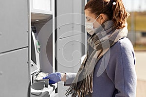 Woman in medical mask and glove with money at atm