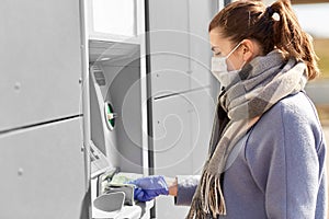 Woman in medical mask and glove with money at atm